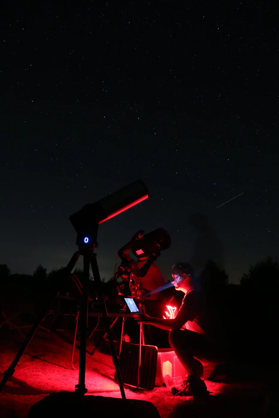Un participant observe au télescope, éclairé de rouge